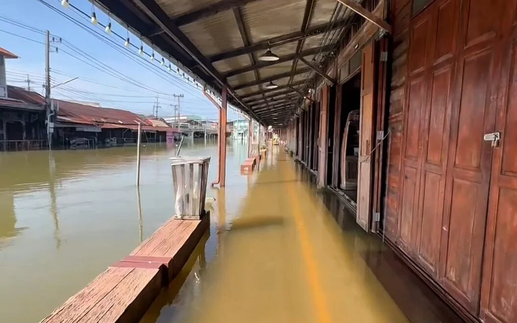 Floodwater inundates a covered walkway at a wooden floating market.