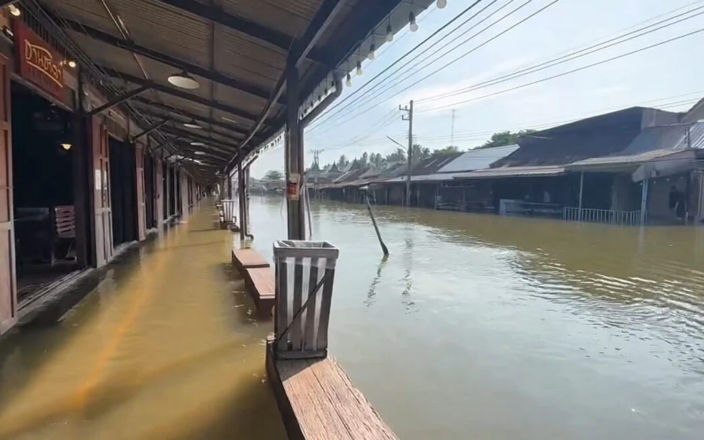 Floodwater inundates a covered walkway and storefronts at a market.