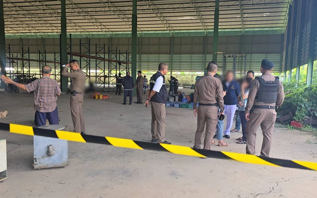 Police and others inspect a large industrial warehouse after a fatal shooting.