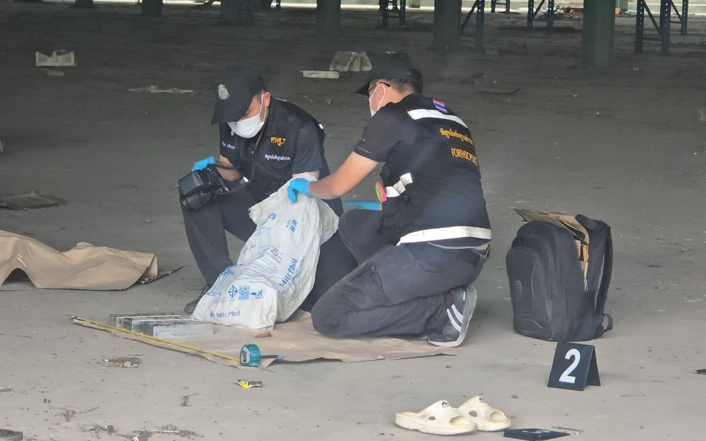 Forensic officers examine evidence at a factory crime scene.