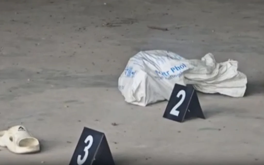 Crime scene markers near covered evidence and scattered shoes on concrete.