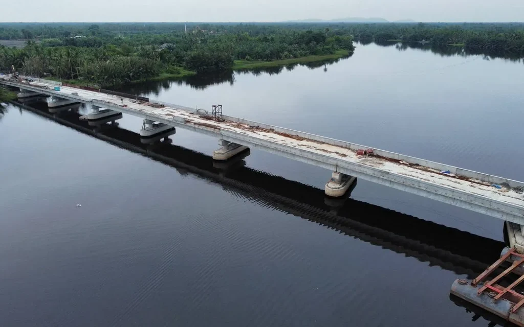 Aerial view of a bridge under construction across a wide river.