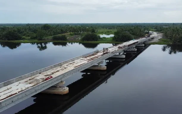 Aerial view of a bridge under construction across a calm river.