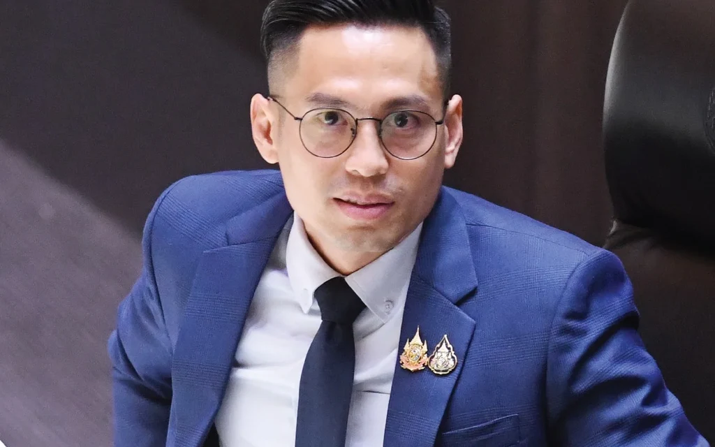 A Thai politician in a suit sitting in parliament.
