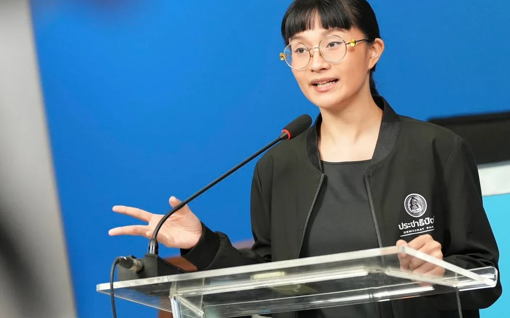 A woman speaking at a podium with a Democratic Party logo.
