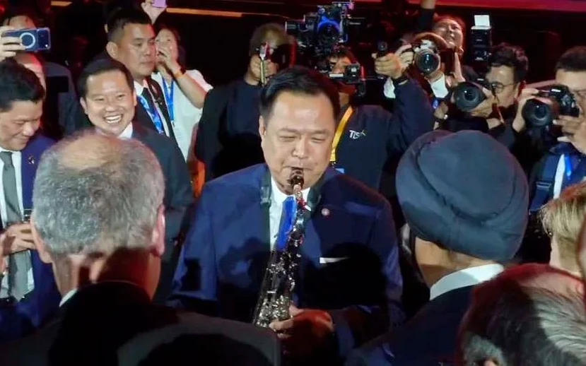 Anutin plays saxophone surrounded by photographers and reception guests