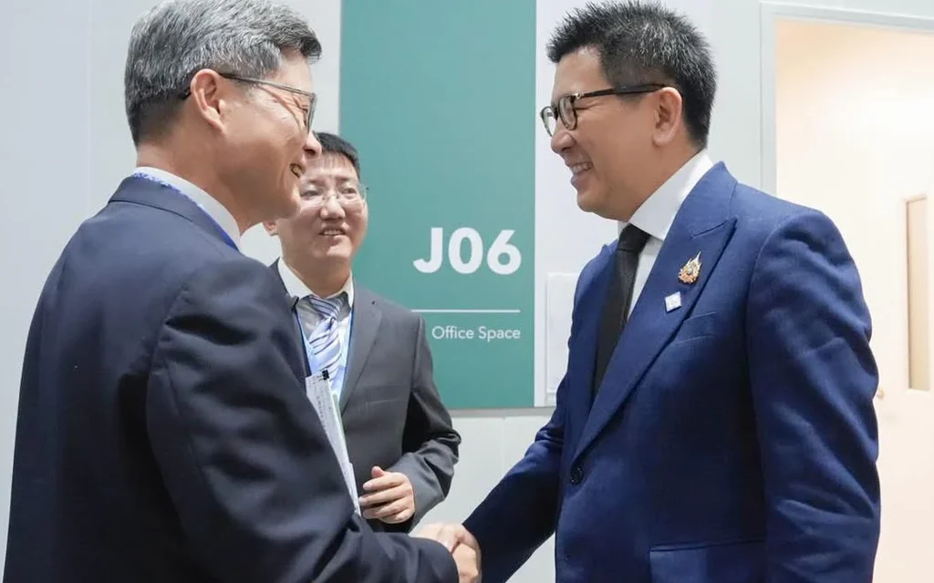 Akaniti Nitithanprapas shaking hands with a Chinese official in an office.
