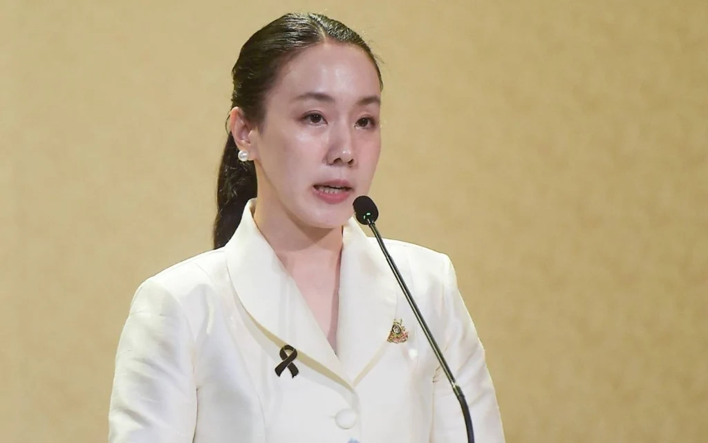 Woman speaking at a podium in a white suit with a microphone
