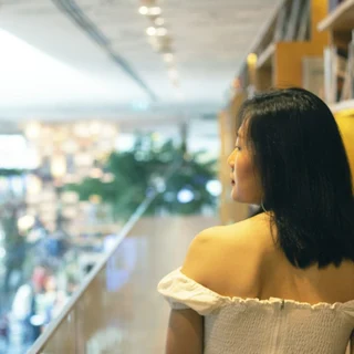 woman in white off shoulder dress standing near glass wall