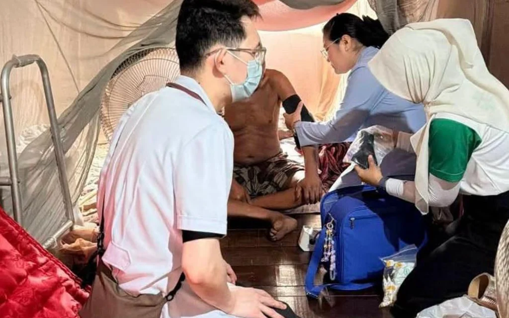 Medical personnel providing care to a patient in a tent.