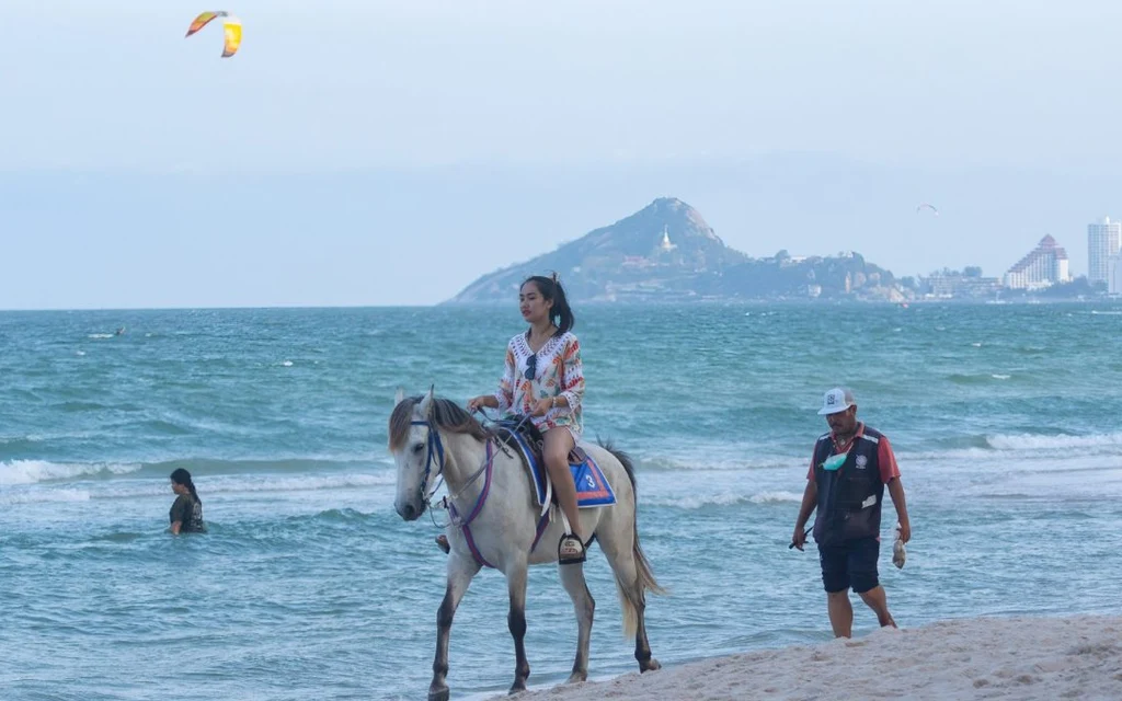 A woman riding a horse on a beach in Thailand.