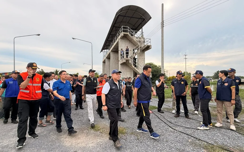 Officials inspect flood conditions near a raised concrete observation structure.
