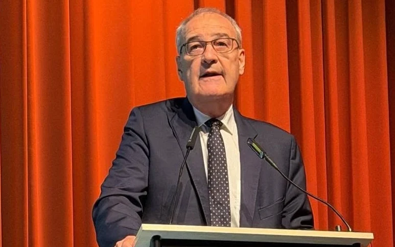 A man in a suit speaking at a podium