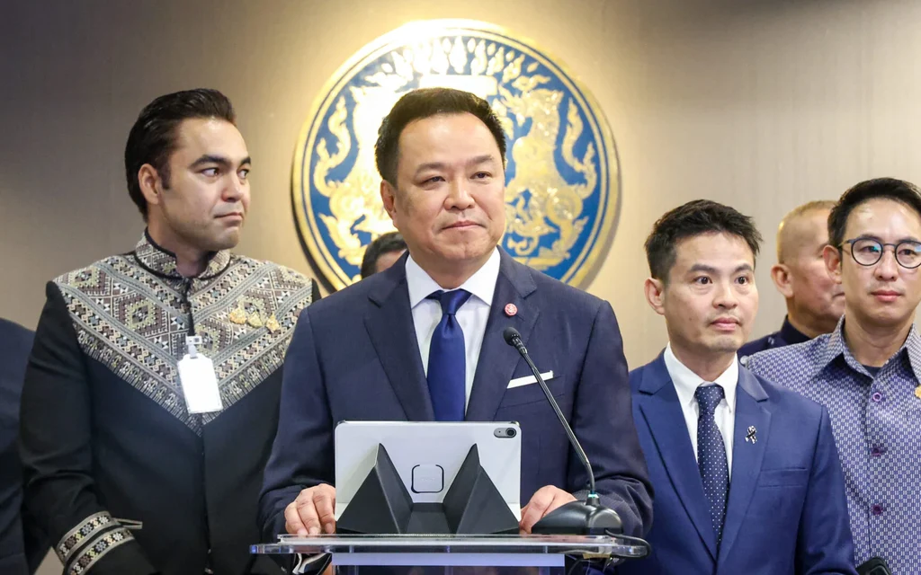 Anutin Charnvirakul speaking at a podium with officials in the background.