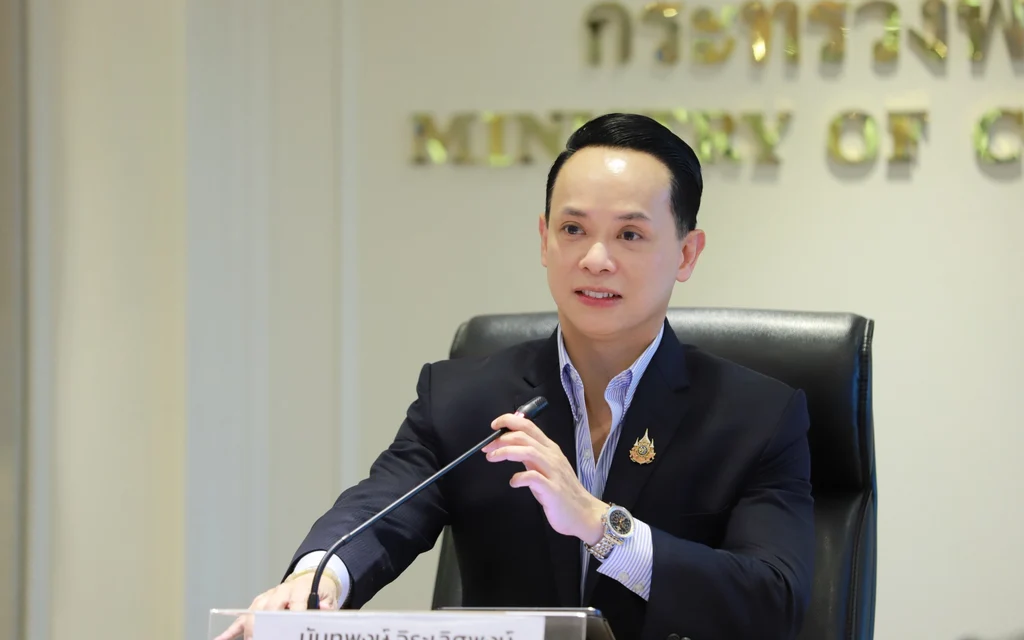 Man speaking at a government press conference behind a desk.