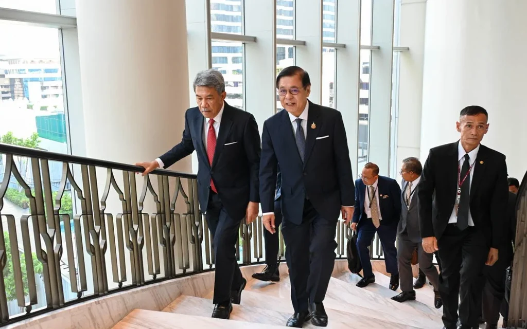 Officials in suits walk up a staircase inside a modern building.