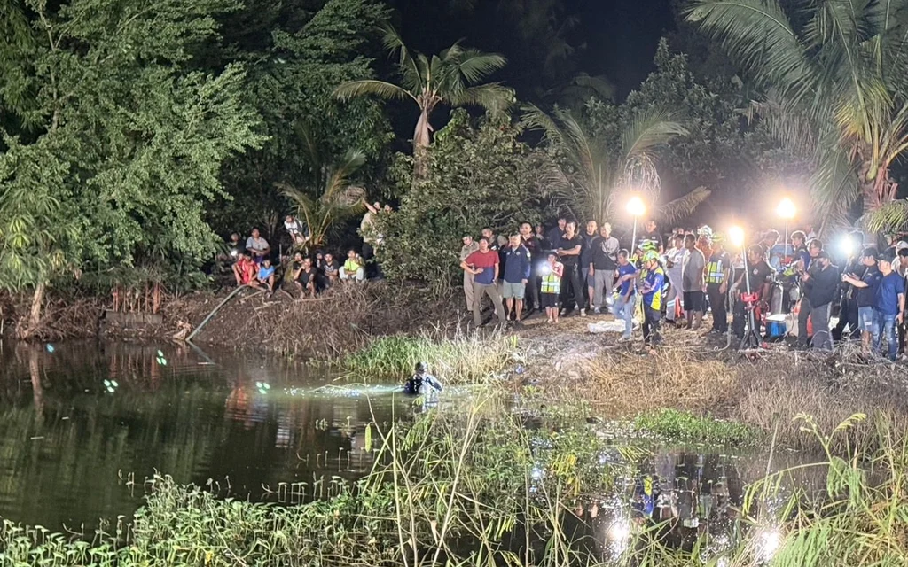 Rescue workers searching for drowning victims in a pond at night.