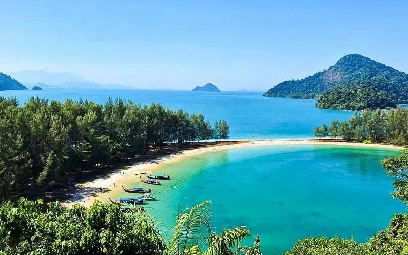 A scenic view of a tropical beach with boats in Thailand.