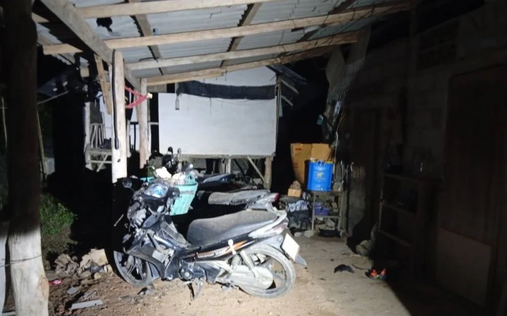 A motorcycle parked under a wooden structure at night.