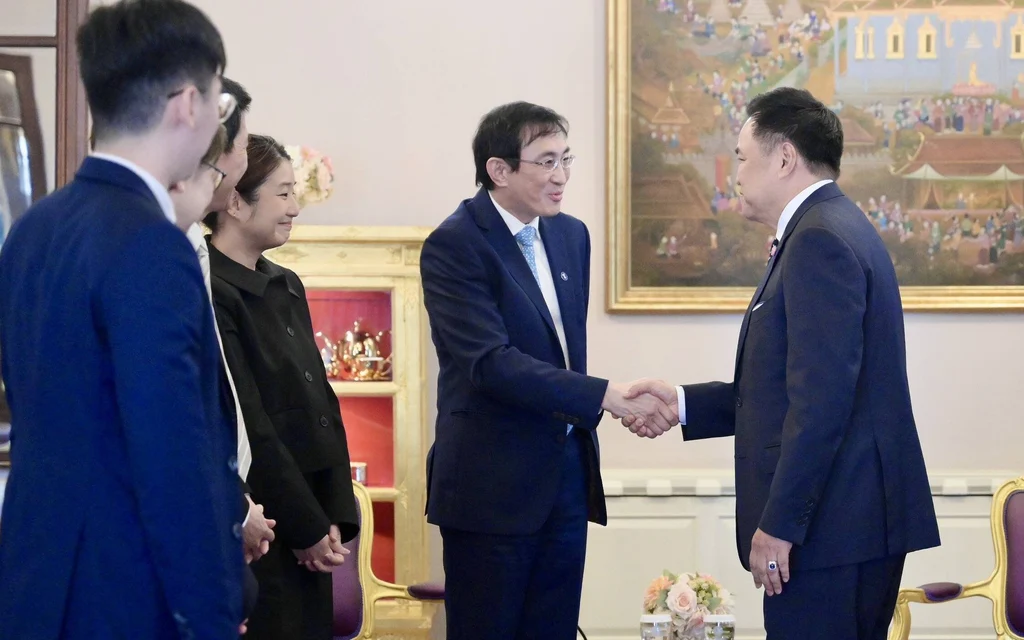 Anutin Charnvirakul shaking hands with Temasek Trust CEO in a meeting room.