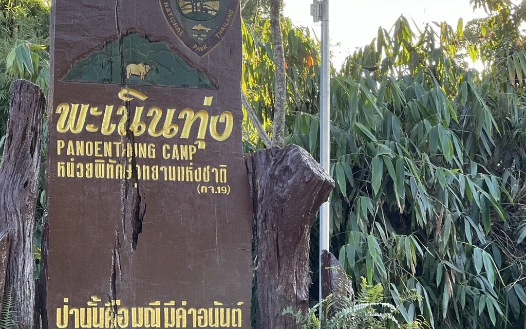 Wooden sign marking Panoen Thung Camp in a forested national park.