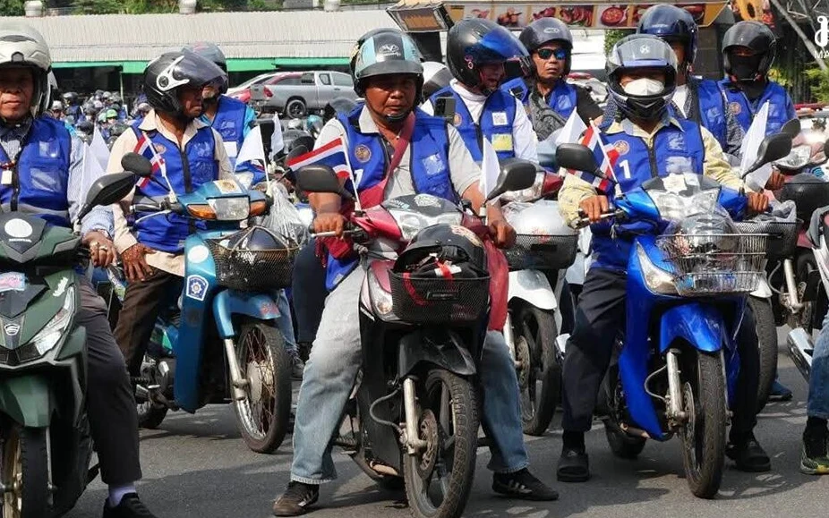 Group of motorcycle taxi drivers wearing blue vests and helmets waiting for customers