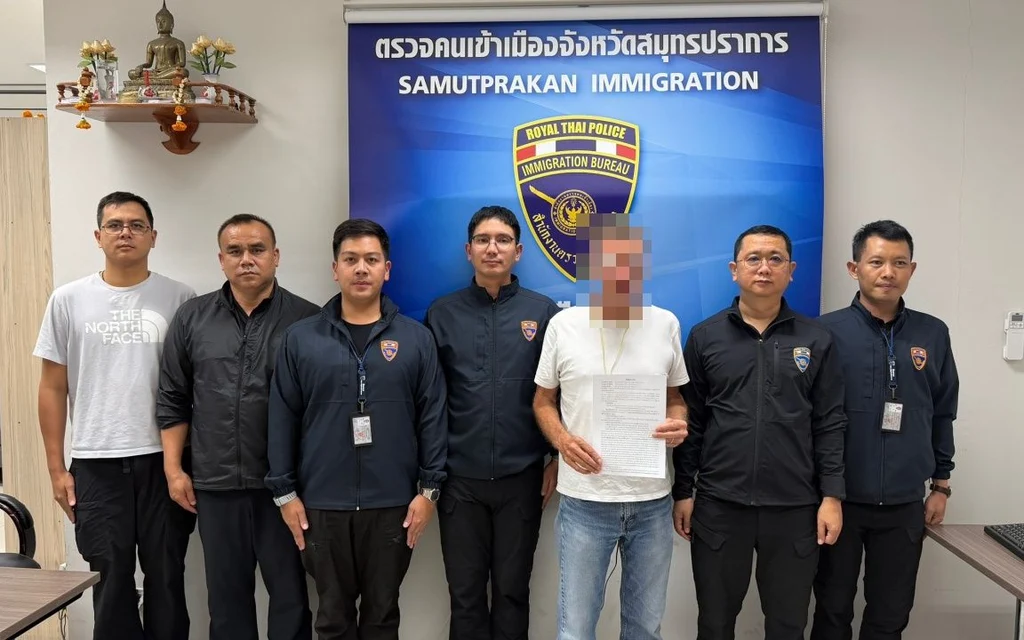 Police officers standing with a man holding documents.