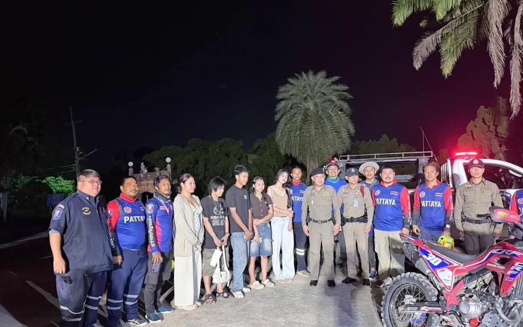 Tourists and officials pose beside rescue vehicles at night.