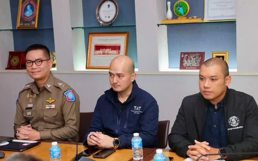 Three men attend a meeting at a table in an office.