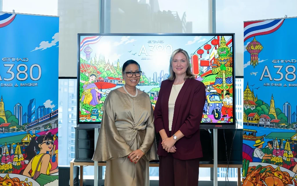Two women pose beside Etihad A380 promotional displays.
