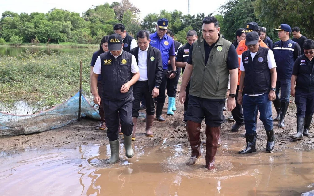 Officials inspect a muddy site near a waterway.
