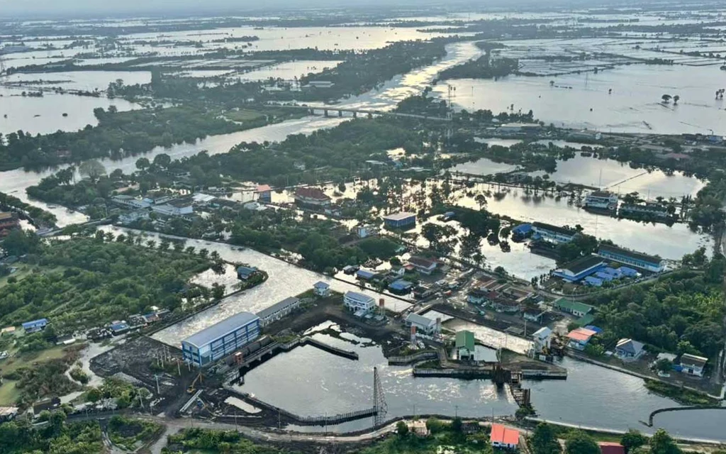 Aerial view of a flooded rural area with buildings and fields.