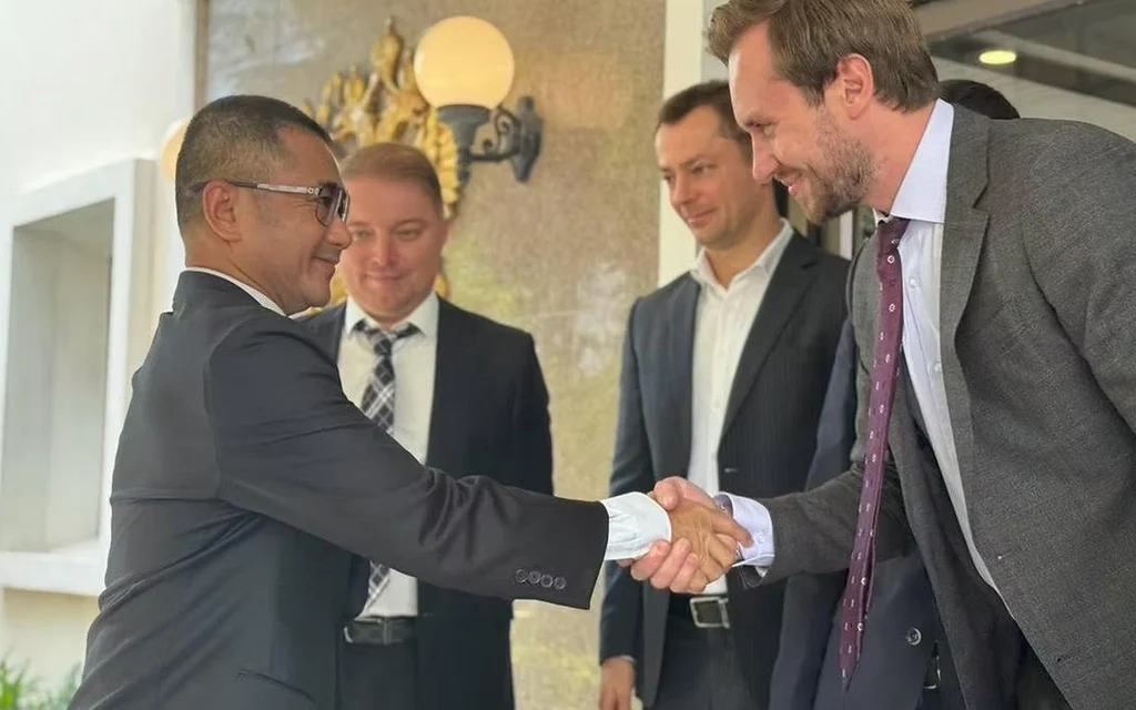 Thai police official shaking hands with a Russian diplomat.