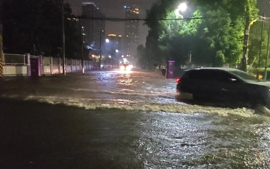 A car driving through a flooded street at night.