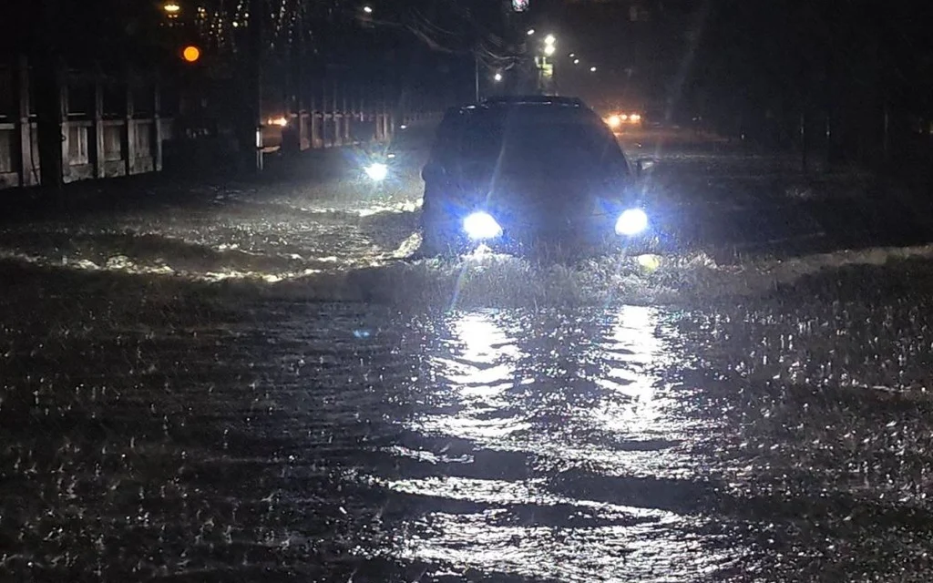 A car driving through a flooded road at night.