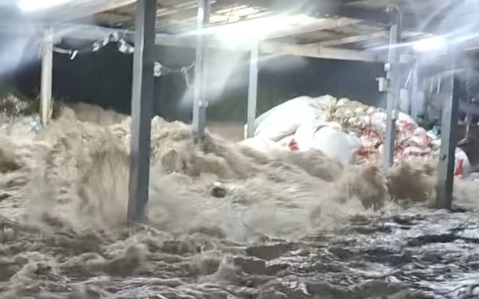 Floodwater rushing through a structure with large white bags.
