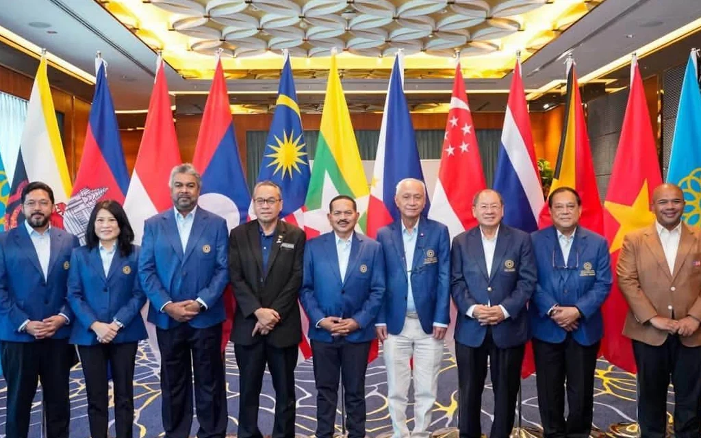 Officials pose together in front of national flags at a conference.