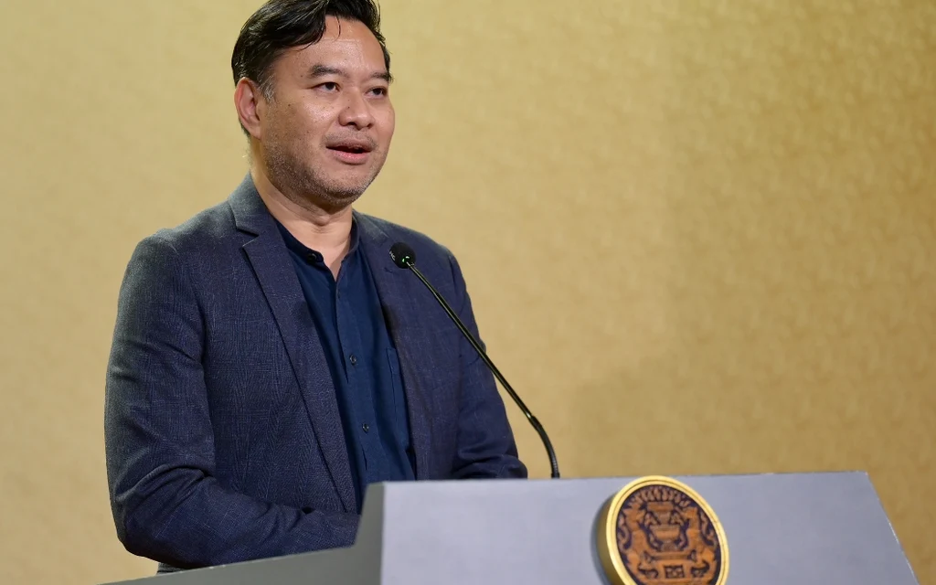 WHO official speaking at a press conference against a World Health Organization backdrop