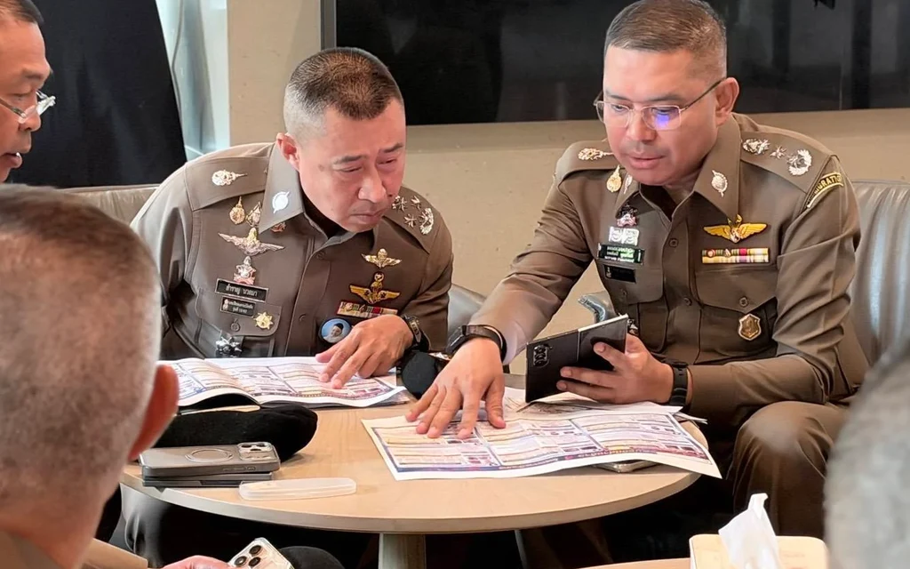 Thai police officers reviewing documents during a meeting.