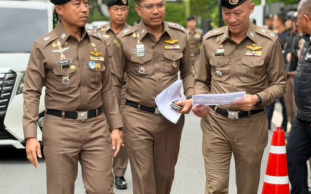 Thai police officers walking outdoors during an operation.