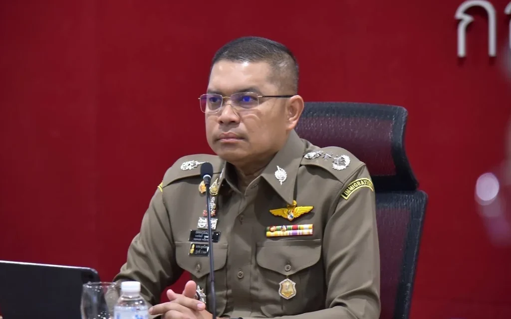 Uniformed Thai police officer seated at a press conference table