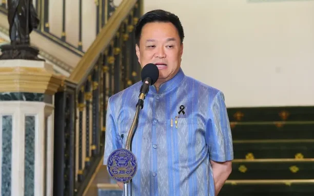 Anutin speaks at a microphone inside an ornate building.