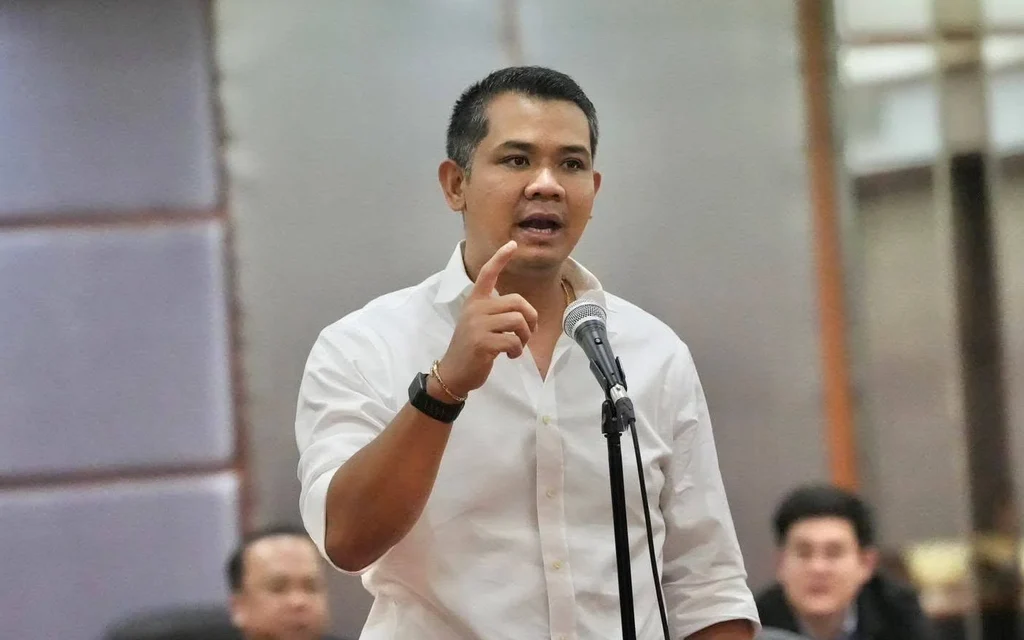 A man in a white shirt speaking into a microphone.