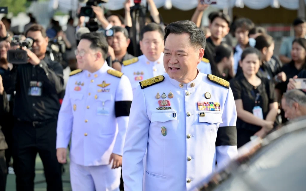 Anutin in formal uniform walks past photographers and attendees.