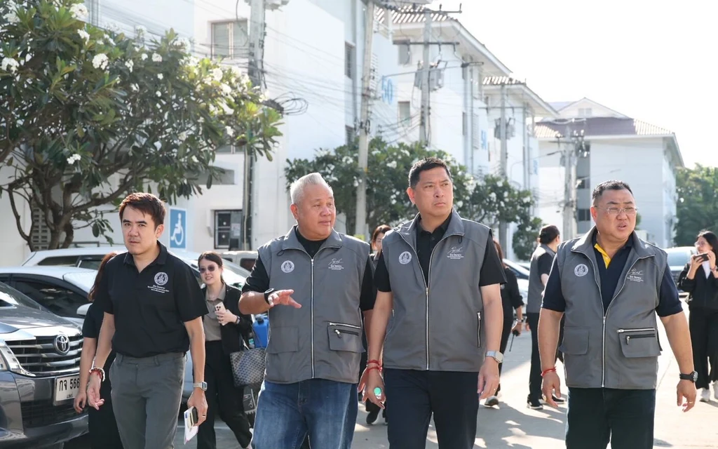 Officials visit a stalled housing project site in bright daylight.