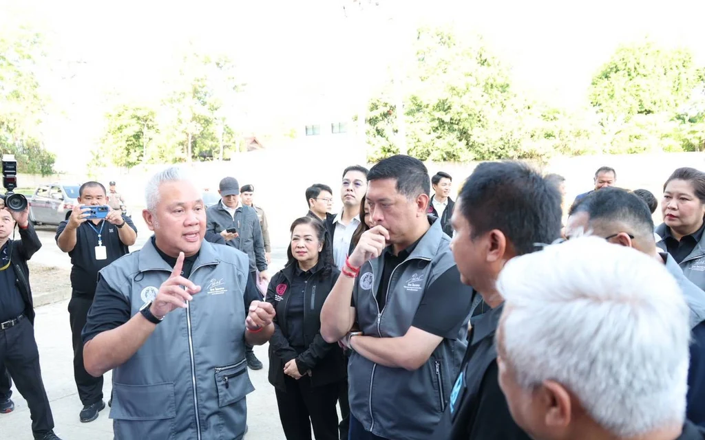 Officials and staff discuss a stalled housing project outdoors.