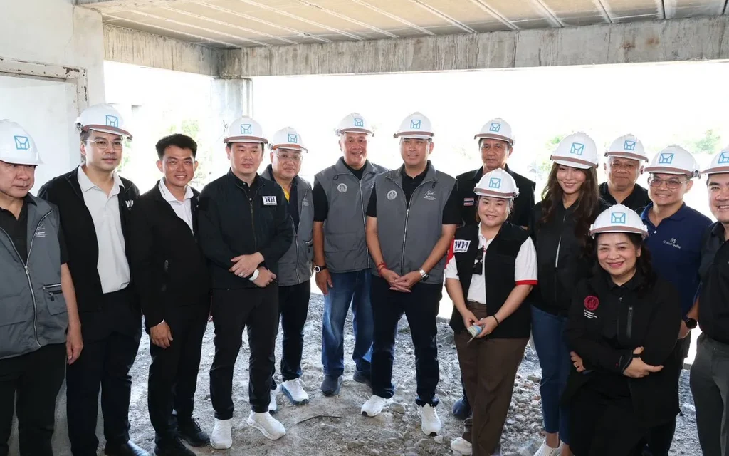 Officials and visitors pose inside a stalled housing project under construction.