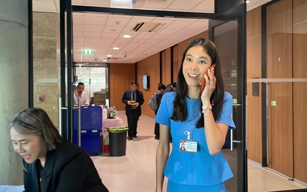 Woman in blue talks on phone in an office doorway.