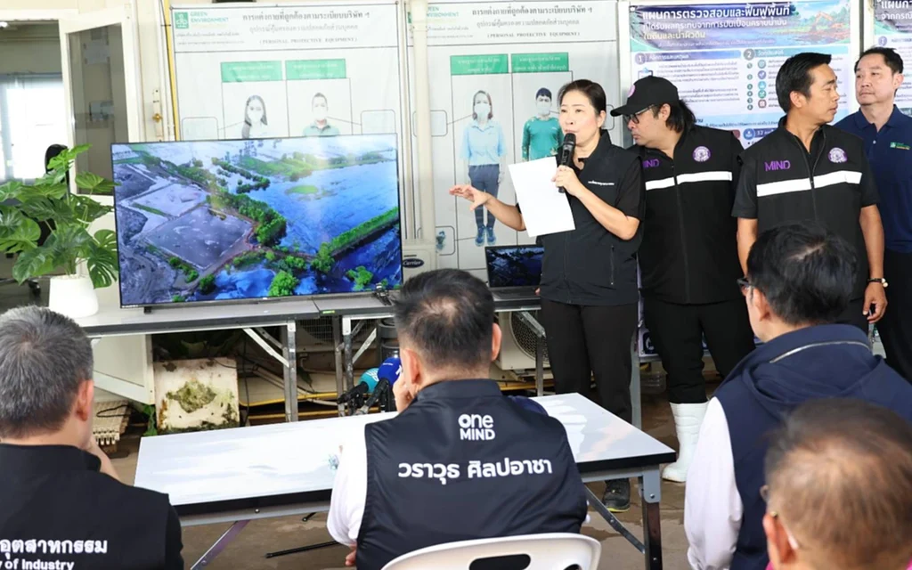 Industry officials brief visitors about an environmental site using a monitor.