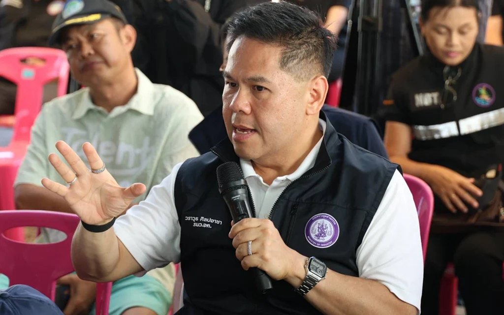 Industry minister speaks into a microphone at a public meeting.